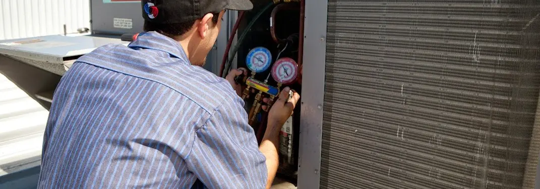 HVAC technician servicing a condenser unit in Harvard