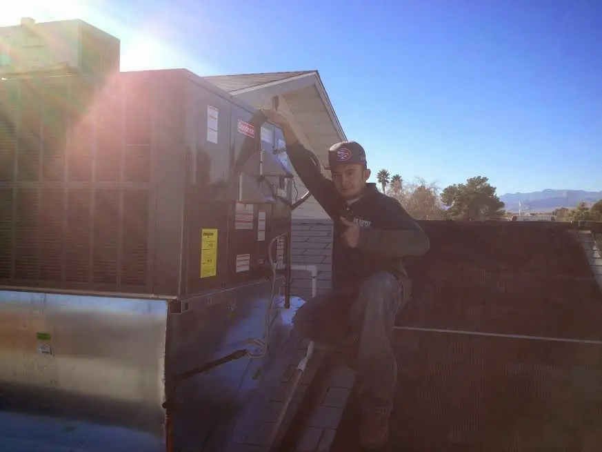 HVAC technician performing AC Tune-Up on a rooftop unit in Harvard